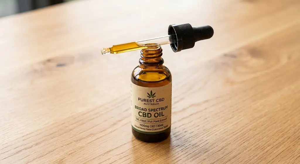 Bottle with dropper containing broad spectrum CBD oil on a clean light wooden table